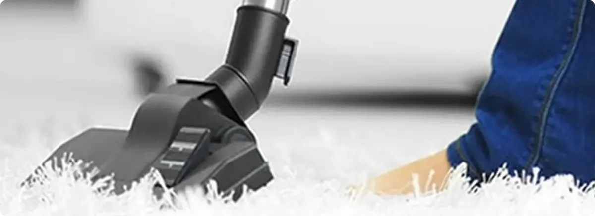 Close-up of a professional vacuuming a white carpet in Raisin City.